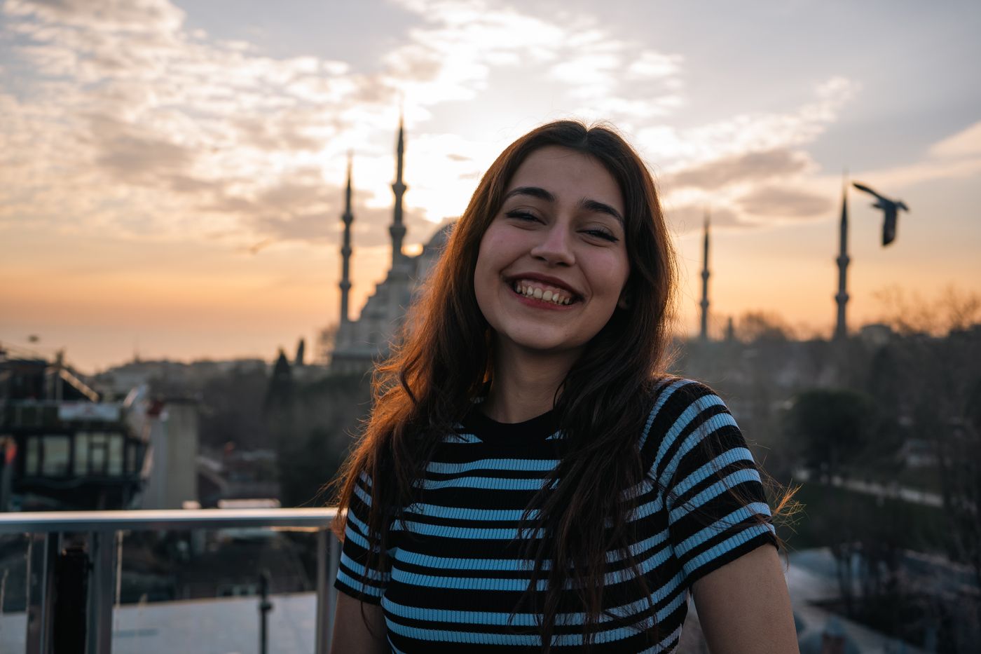 A smiling young woman at sunset while travelling abroad