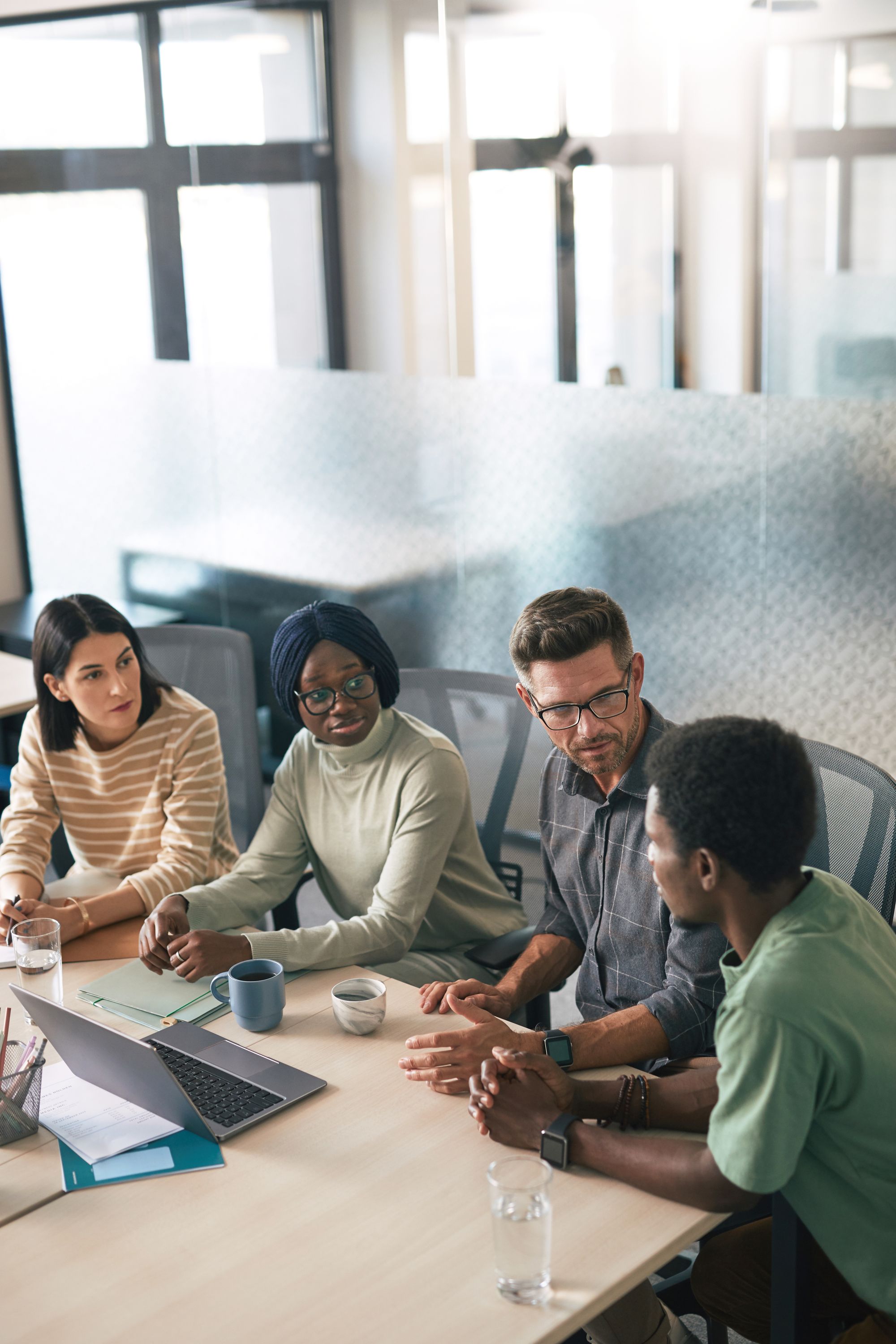 A diverse group of colleagues collaborating around a table in a bright modern office